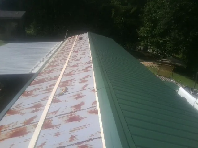 Old rusted panels beside newly installed green metal roofing — Wind Damage Roof Repair by Roofing Brothers in South Barre