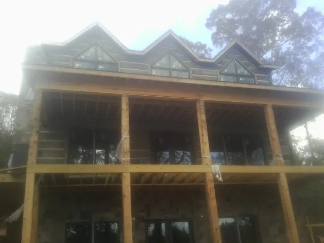 Dormers and porch framing on a large log home under construction — Roof Coating work by our crew in South Barre