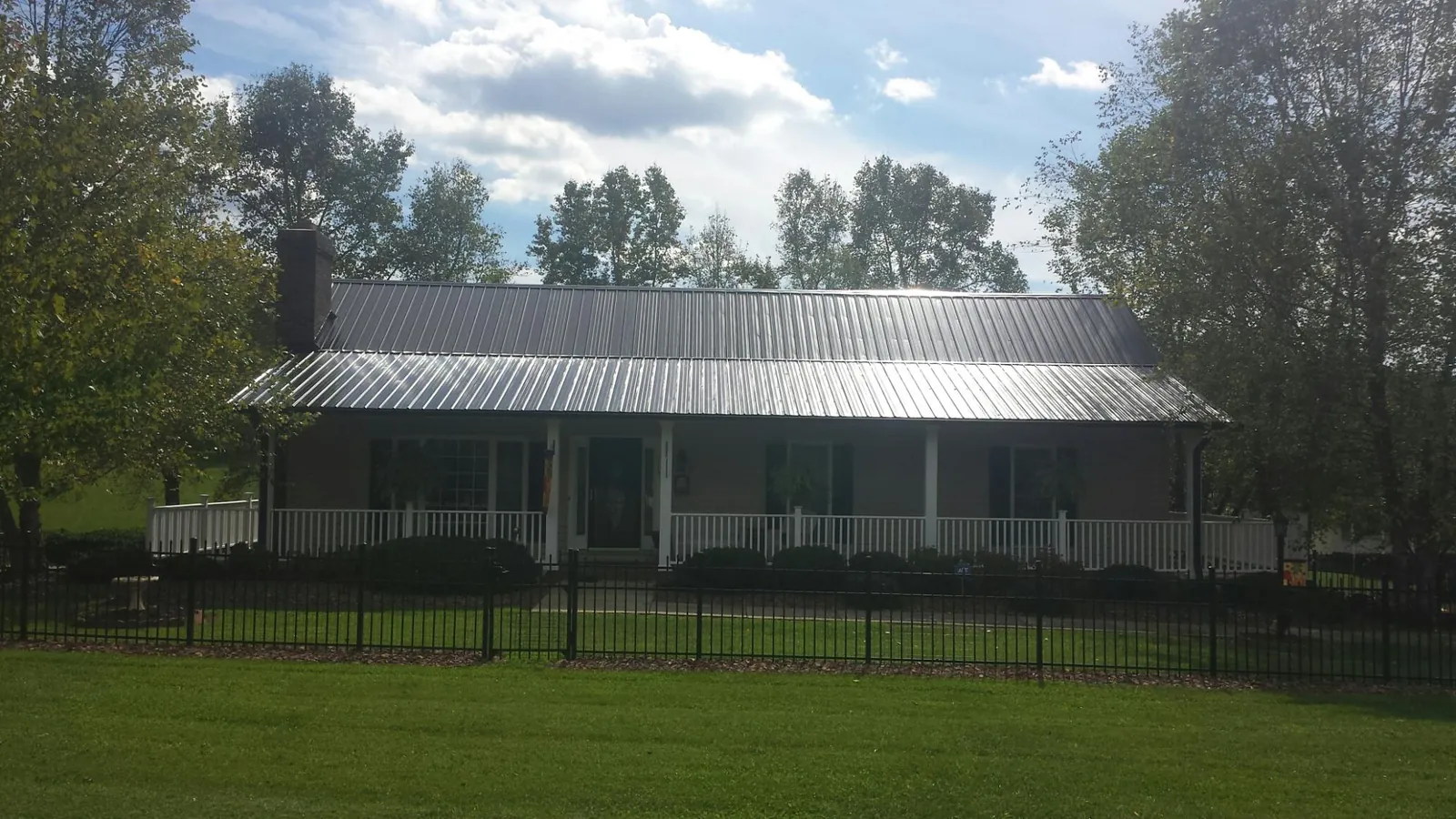 Gray metal roof on a brick ranch with a full width front porch — Gutter Guard Installation work by our crew in South Barre