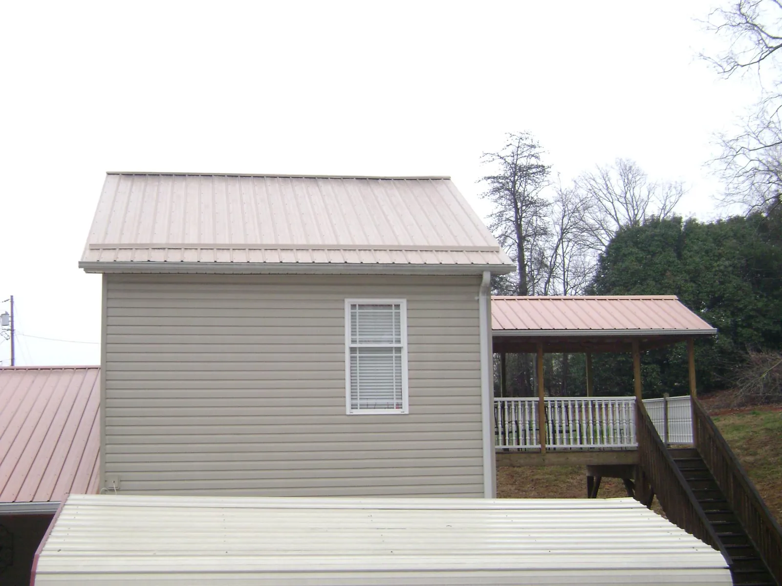 Tan metal roofs on a two story addition and attached porch, from a Roof Replacement job in South Barre