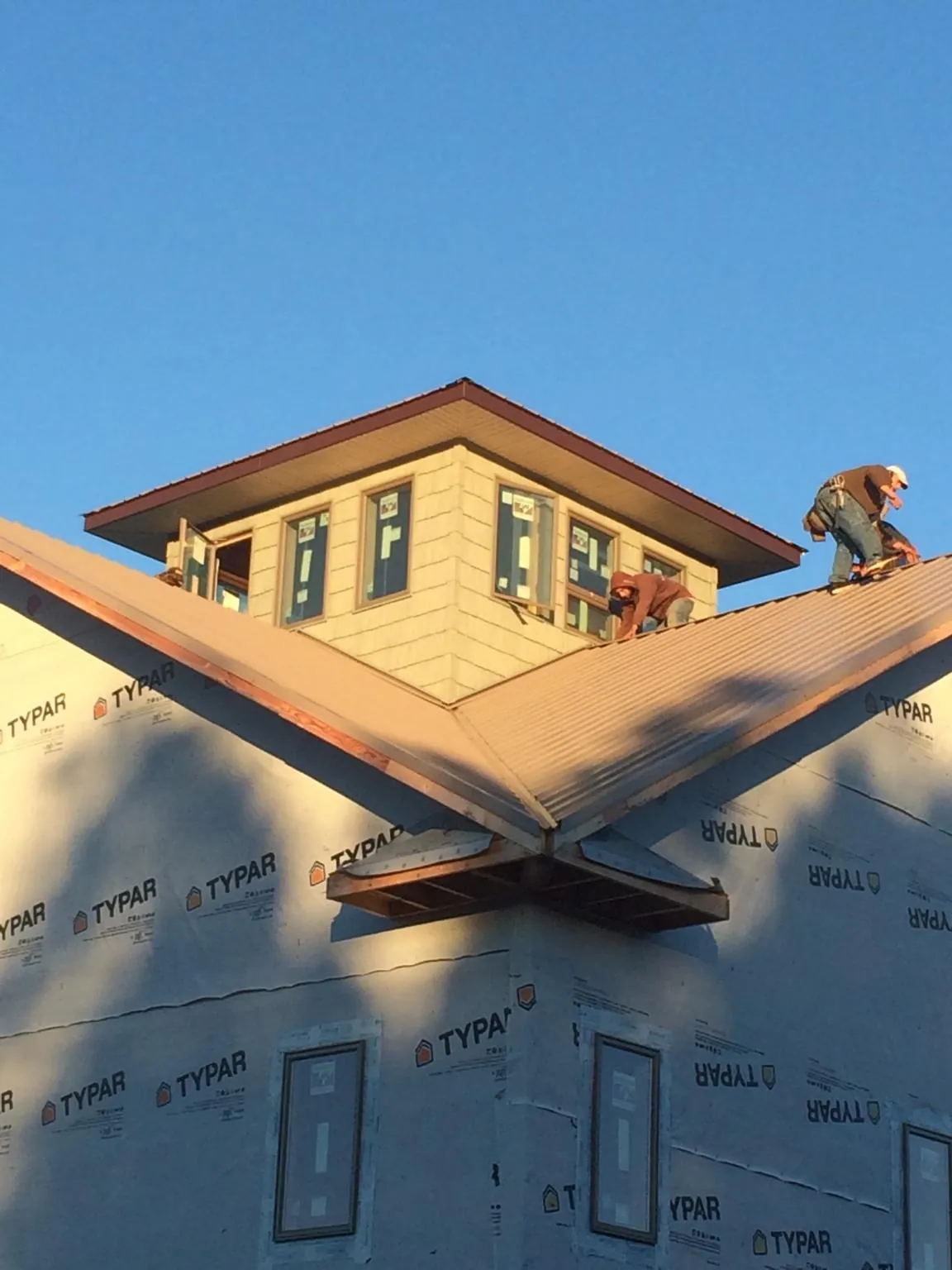 Roofers working around a rooftop cupola on a new metal roof at sunset — Roof Waterproofing in South Barre by Roofing Brothers
